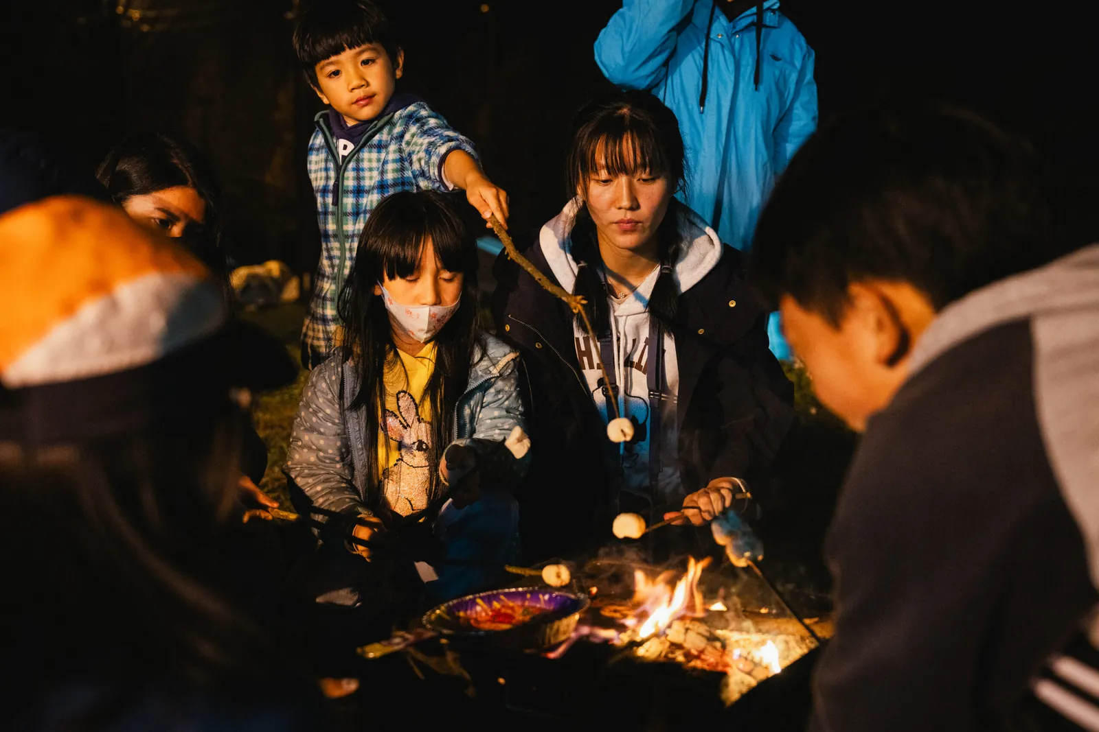 首頁 4 孩子與成人圍著營火烤棉花糖